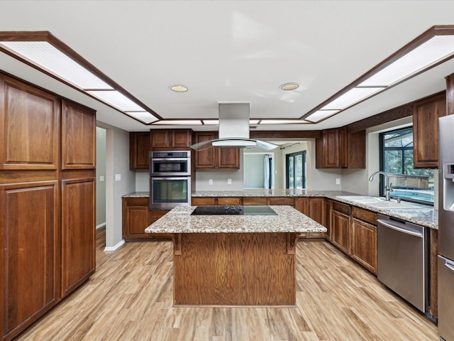 kitchen with light wood-style flooring, appliances with stainless steel finishes, a sink, and a center island