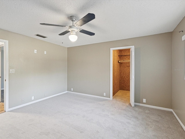 empty room with light carpet, visible vents, a textured ceiling, and baseboards