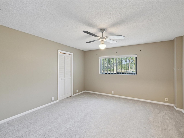 empty room featuring light carpet, a textured ceiling, a ceiling fan, and baseboards