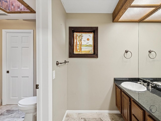 bathroom with toilet, baseboards, and vanity