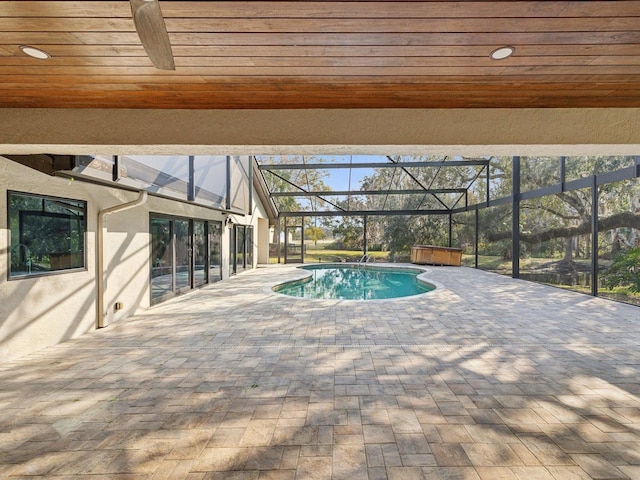 view of pool featuring a patio, glass enclosure, and a hot tub