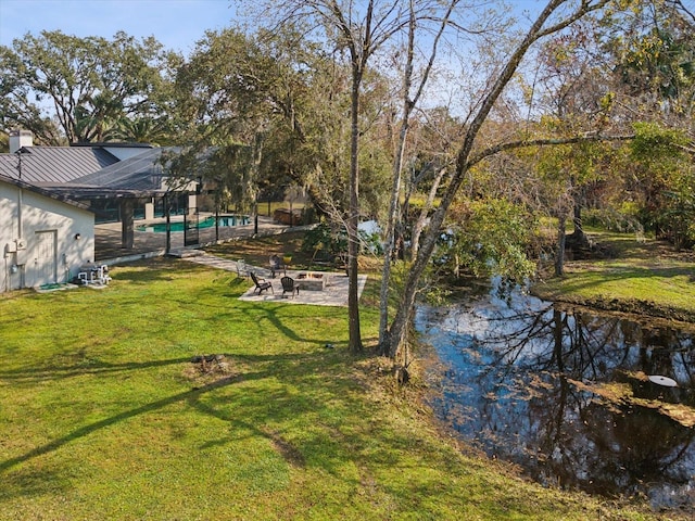 view of yard with an outdoor fire pit, a water view, and an outdoor pool