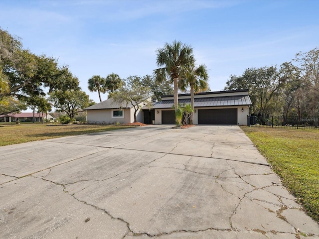 view of front facade featuring an attached garage, fence, driveway, stucco siding, and a front yard