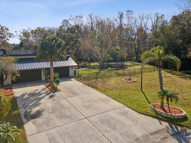 view of yard with a garage, concrete driveway, and fence private yard