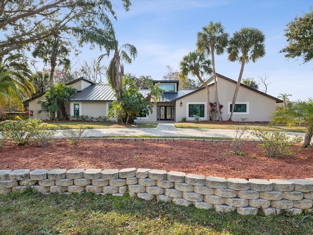 mid-century home featuring metal roof, a standing seam roof, and stucco siding