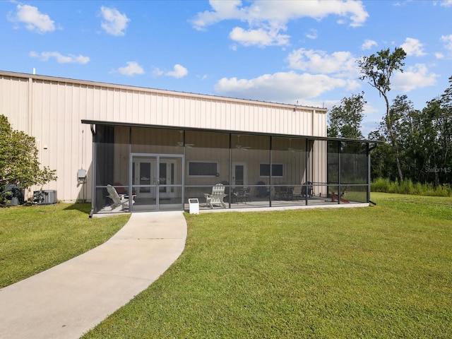 rear view of property with a patio, a yard, a sunroom, and central air condition unit