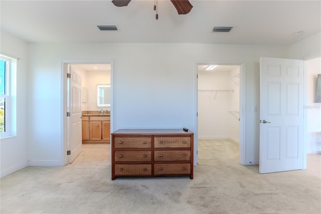 carpeted bedroom with multiple windows, a walk in closet, connected bathroom, and a closet