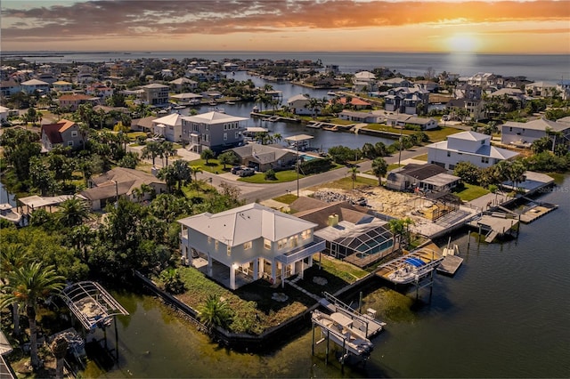 aerial view at dusk featuring a water view