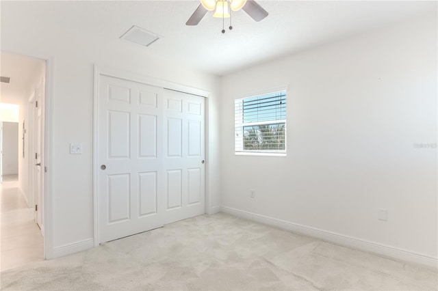 unfurnished bedroom featuring ceiling fan, a closet, and light carpet