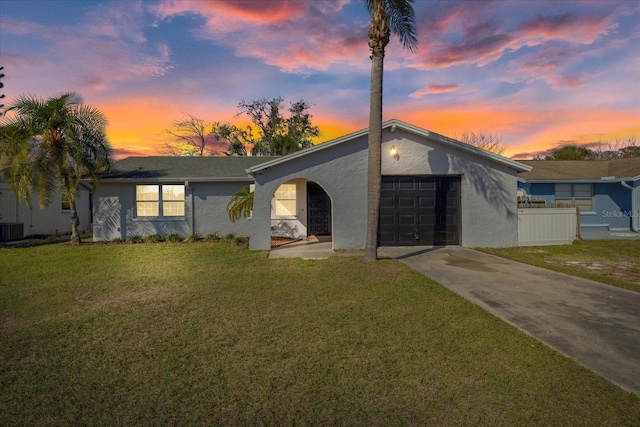 view of front of property with cooling unit, a garage, and a yard