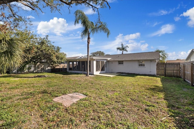 rear view of property with a patio, a sunroom, and a yard