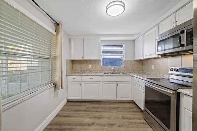 kitchen featuring white cabinetry, sink, light hardwood / wood-style floors, and appliances with stainless steel finishes