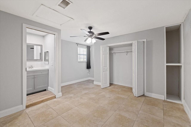 unfurnished bedroom with connected bathroom, sink, light tile patterned floors, ceiling fan, and a closet