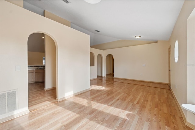 empty room with vaulted ceiling and light hardwood / wood-style flooring