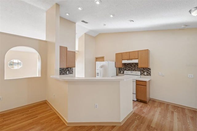 kitchen featuring white appliances, kitchen peninsula, a textured ceiling, and light wood-type flooring