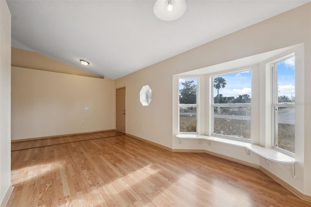 spare room featuring lofted ceiling and light wood-type flooring