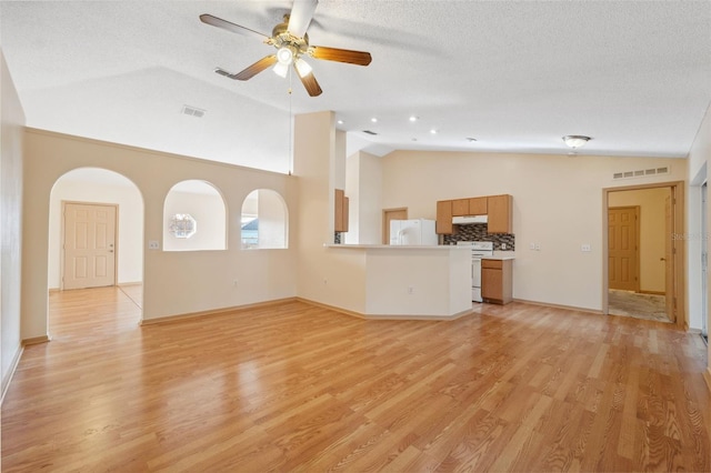 unfurnished living room featuring ceiling fan, vaulted ceiling, light hardwood / wood-style flooring, and a textured ceiling