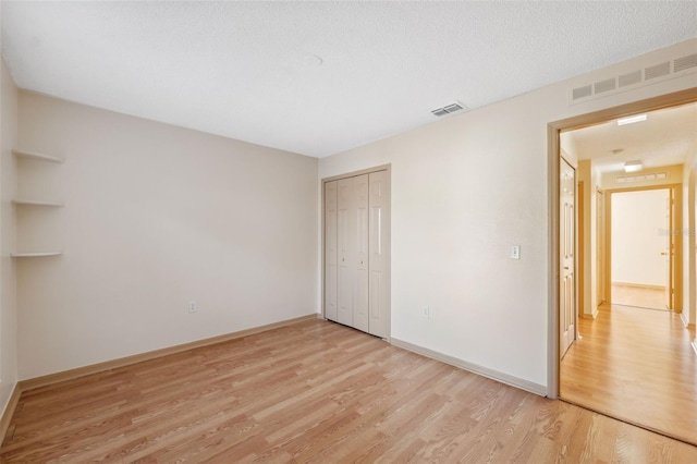 unfurnished bedroom with a closet, a textured ceiling, and light hardwood / wood-style flooring