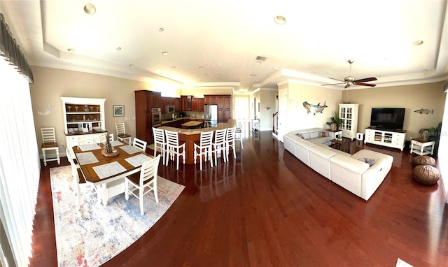 living room featuring dark hardwood / wood-style flooring, a raised ceiling, and ceiling fan