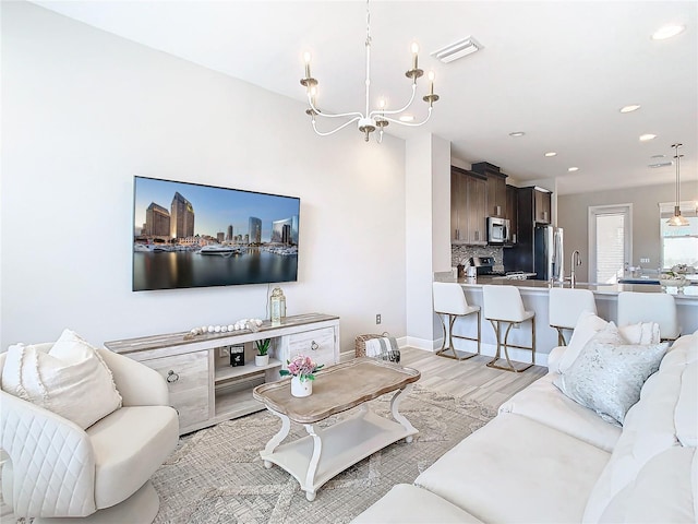 living room with sink, light hardwood / wood-style flooring, and a chandelier