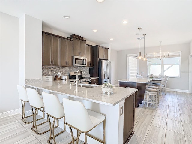 kitchen featuring sink, hanging light fixtures, appliances with stainless steel finishes, a kitchen breakfast bar, and kitchen peninsula