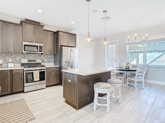 kitchen with a kitchen island, appliances with stainless steel finishes, a wealth of natural light, decorative light fixtures, and backsplash