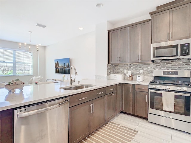 kitchen featuring sink, tasteful backsplash, kitchen peninsula, pendant lighting, and stainless steel appliances