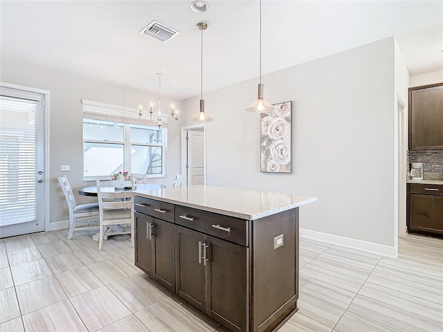 kitchen with pendant lighting, light stone counters, dark brown cabinetry, and a chandelier