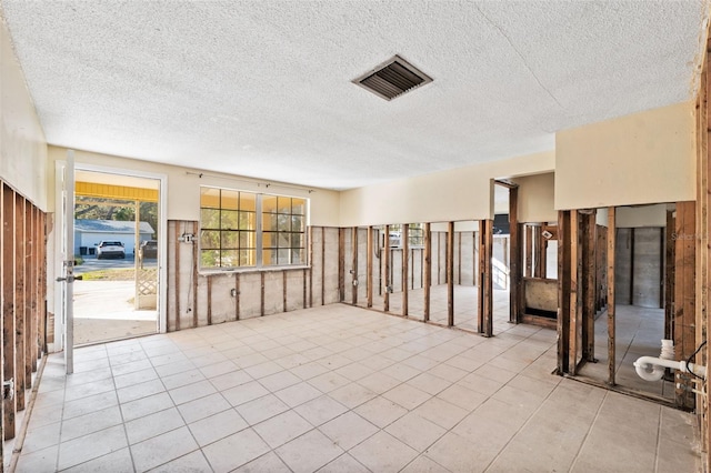 spare room featuring a textured ceiling and light tile patterned floors