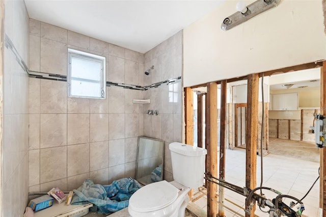 bathroom featuring tile walls, toilet, and a tile shower