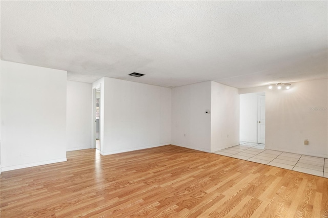 unfurnished room featuring light hardwood / wood-style floors and a textured ceiling