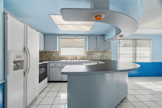 kitchen with backsplash, white appliances, kitchen peninsula, and light tile patterned flooring