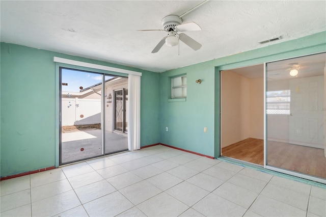 tiled empty room featuring ceiling fan and a textured ceiling