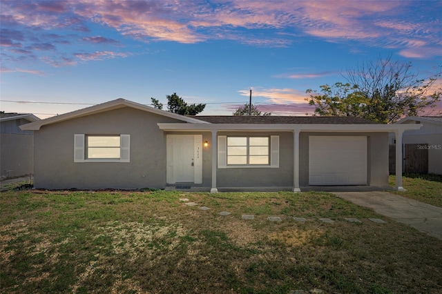 single story home featuring driveway, a garage, fence, a yard, and stucco siding