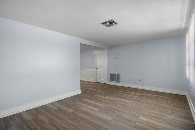 spare room with baseboards, visible vents, and wood finished floors