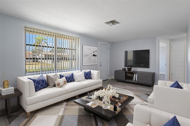 living area with wood finished floors, visible vents, and baseboards