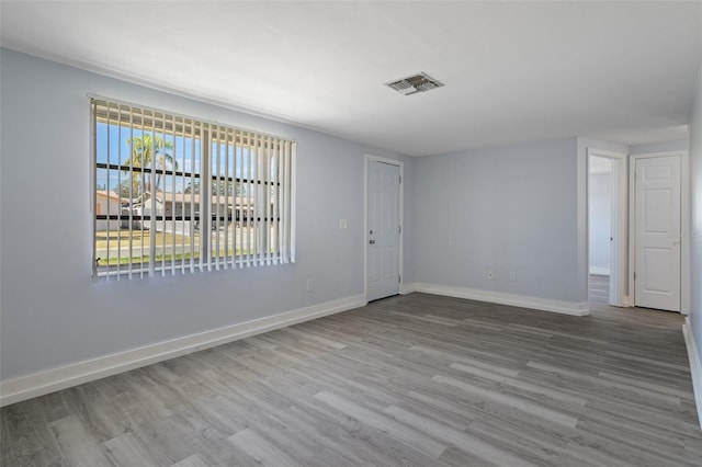 unfurnished room with wood finished floors, visible vents, and baseboards