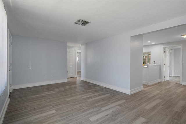 empty room featuring baseboards, visible vents, wood finished floors, and recessed lighting