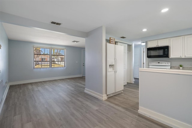 kitchen with white refrigerator with ice dispenser, stove, white cabinets, black microwave, and baseboards