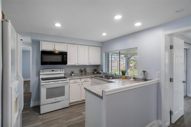 kitchen featuring white appliances, white cabinets, a sink, and wood finished floors