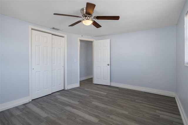 unfurnished bedroom featuring baseboards, a closet, visible vents, and wood finished floors