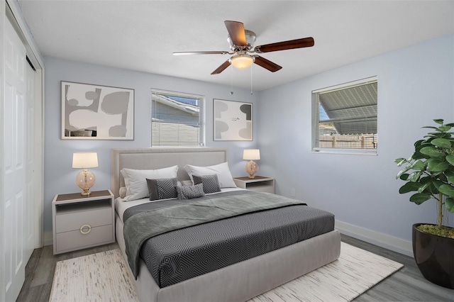 bedroom with a closet, wood finished floors, a ceiling fan, and baseboards