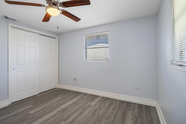 unfurnished bedroom featuring a closet, wood finished floors, visible vents, and baseboards