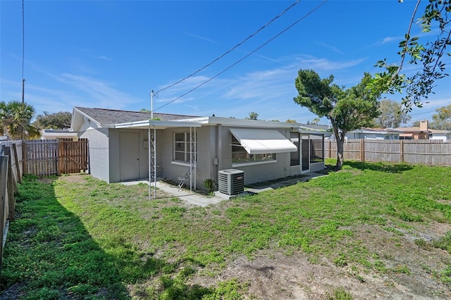 back of house featuring a fenced backyard, central AC, and a yard