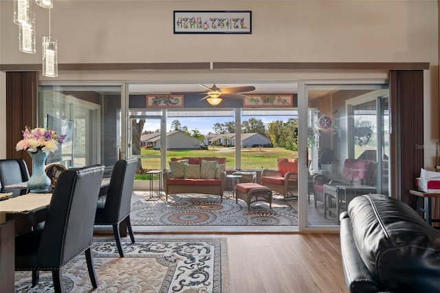 dining room with a towering ceiling, a wealth of natural light, ceiling fan, and light hardwood / wood-style flooring