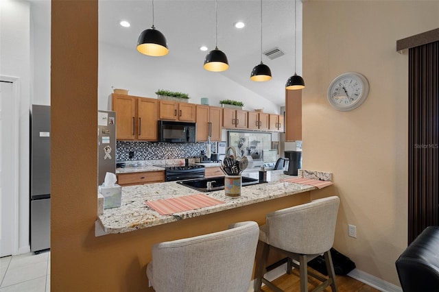 kitchen featuring pendant lighting, kitchen peninsula, light stone countertops, and black appliances