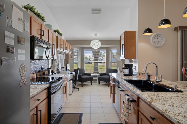 kitchen with sink, light stone counters, light tile patterned floors, pendant lighting, and black appliances