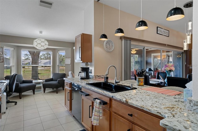 kitchen with light tile patterned flooring, decorative light fixtures, dishwasher, sink, and light stone countertops