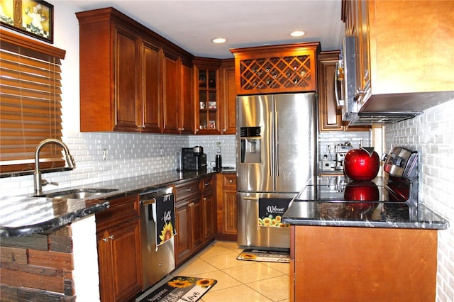 kitchen featuring light tile patterned floors, sink, stainless steel appliances, and dark stone counters