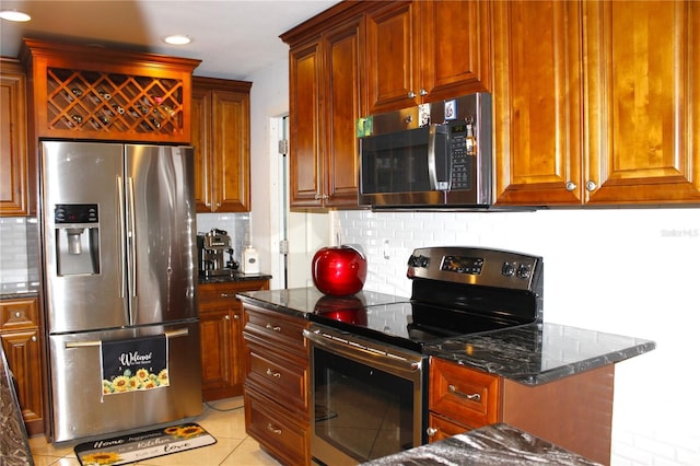 kitchen featuring dark stone countertops, backsplash, light tile patterned floors, and appliances with stainless steel finishes